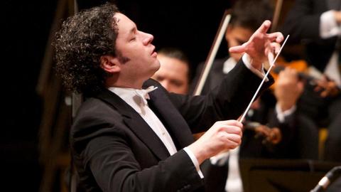 Dirigent Dudamel mit großer Geste vor einem Orchester stehend
