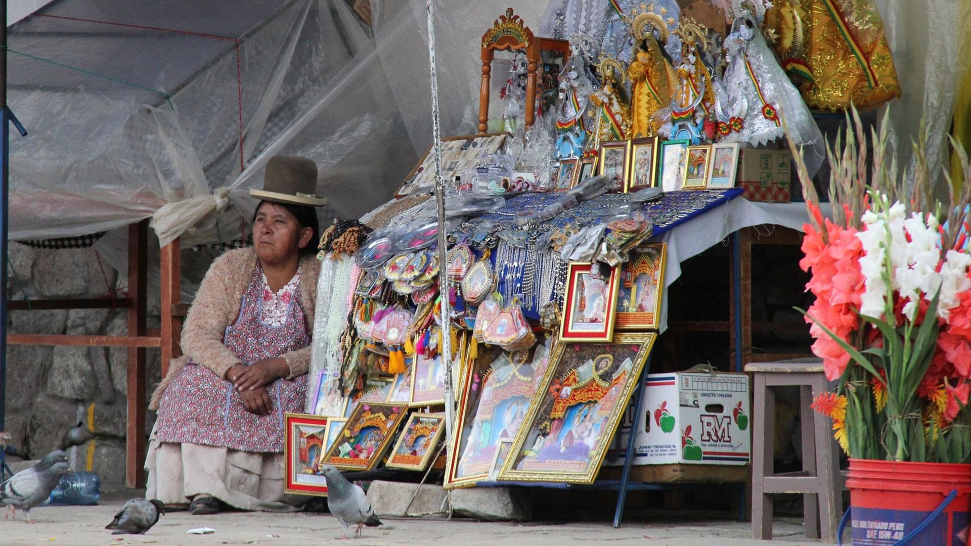 Eine Verkäuferin sitzt neben Ihrem Stand mit Heiligenbildchen und Schmuck an der Kathedrale von Copacabana. Eine Verkäuferin sitzt neben Ihrem Stand mit Heiligenbildchen und Schmuck an der Kathedrale von Copacabana.