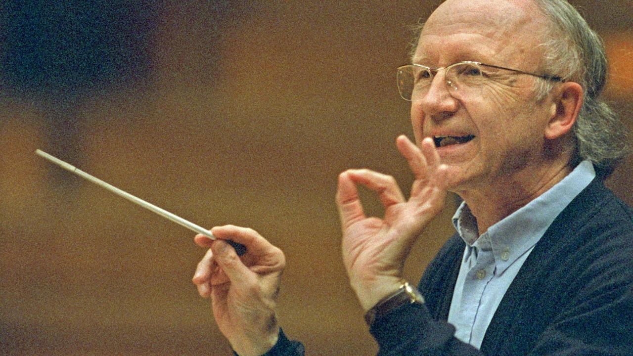 Der Dirigent Heinz Holliger in einer seitlichen Aufnahme, dirigiert mit Taktstock und Hand. Der Dirigent Heinz Holliger in einer seitlichen Aufnahme, dirigiert mit Taktstock und Hand.