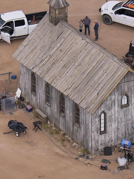 Das aus der Luft aufgenommene Foto zeigt eine aus Holz gebaute Kirche. Davor Menschen, Filmkameras auf Stativen, sowie ein rotes und zwei weiße Fahrzeuge.