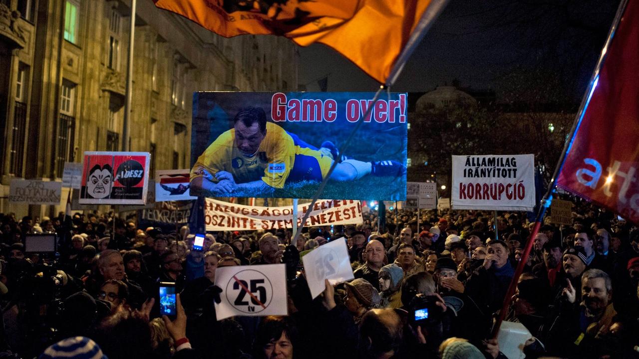 Demonstranten protestieren mit großen Plakaten und Flaggen gegen die ungarische Regierung.