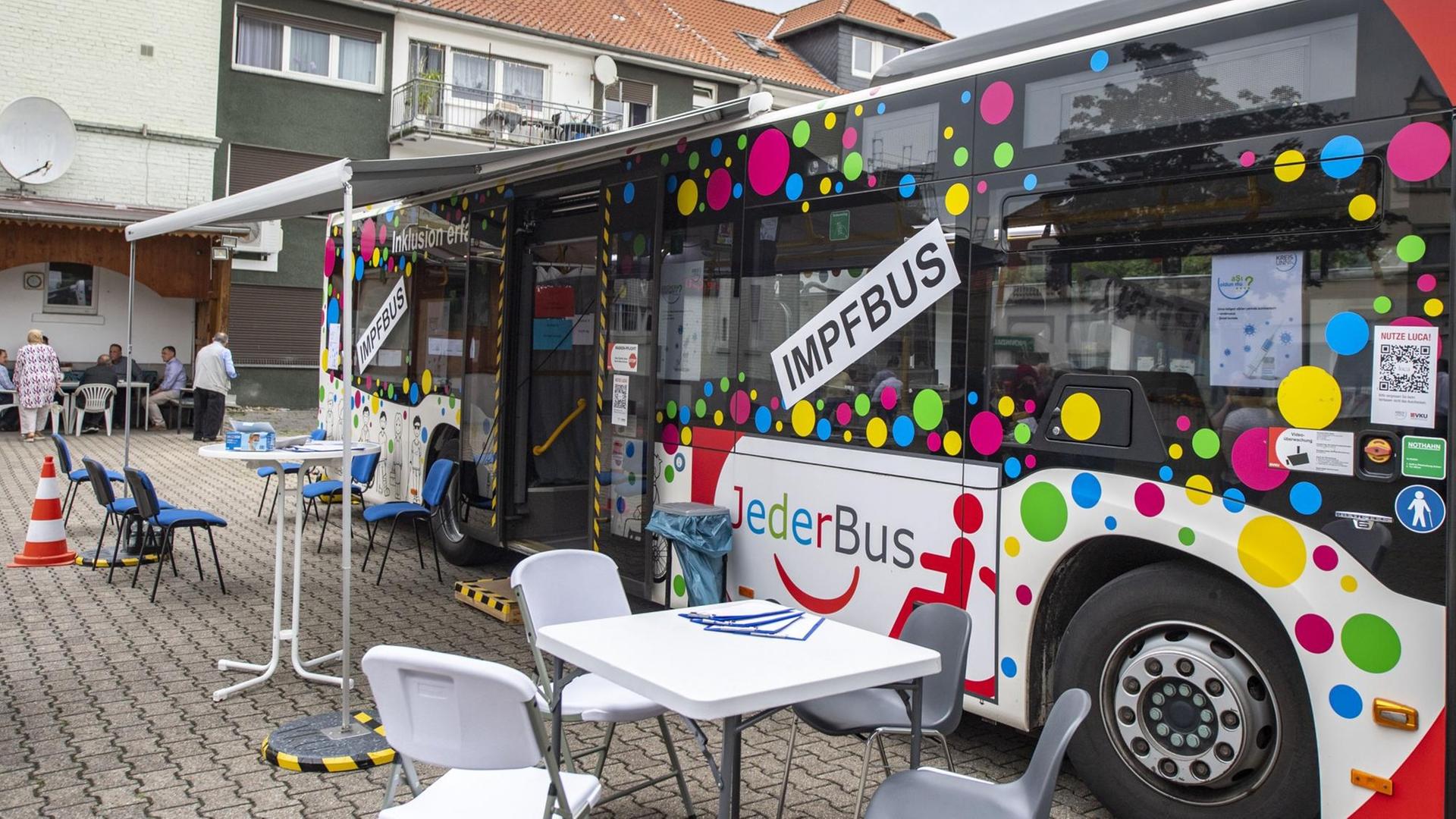 Ein bunt beklebter Bus mit der Auffschrift "Impfbus" steht auf einen Parkplatz. Ein bunt beklebter Bus mit der Auffschrift "Impfbus" steht auf einen Parkplatz.