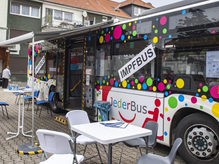 Ein bunt beklebter Bus mit der Auffschrift "Impfbus" steht auf einen Parkplatz.