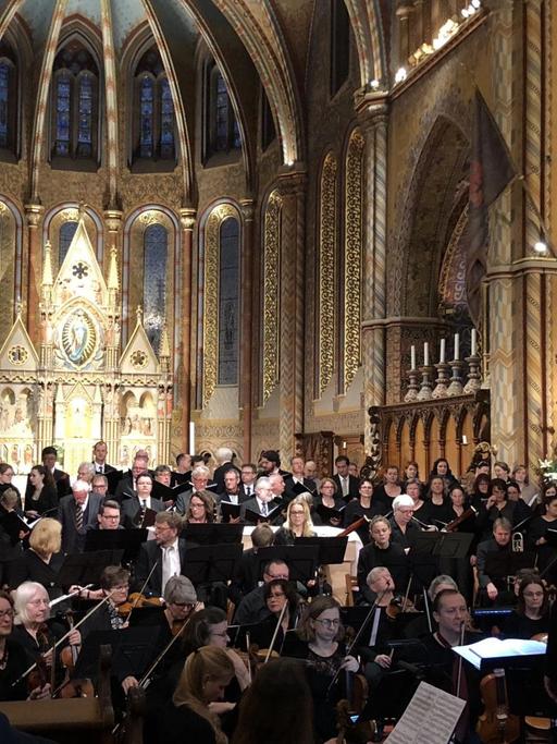 Chor und Orchester vor goldenem Altar in einer Kirche