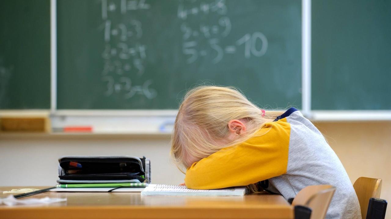 Ein Schulkind liegt niedergeschlagen auf seiner Schulbank. Ein Schulkind liegt niedergeschlagen auf seiner Schulbank.