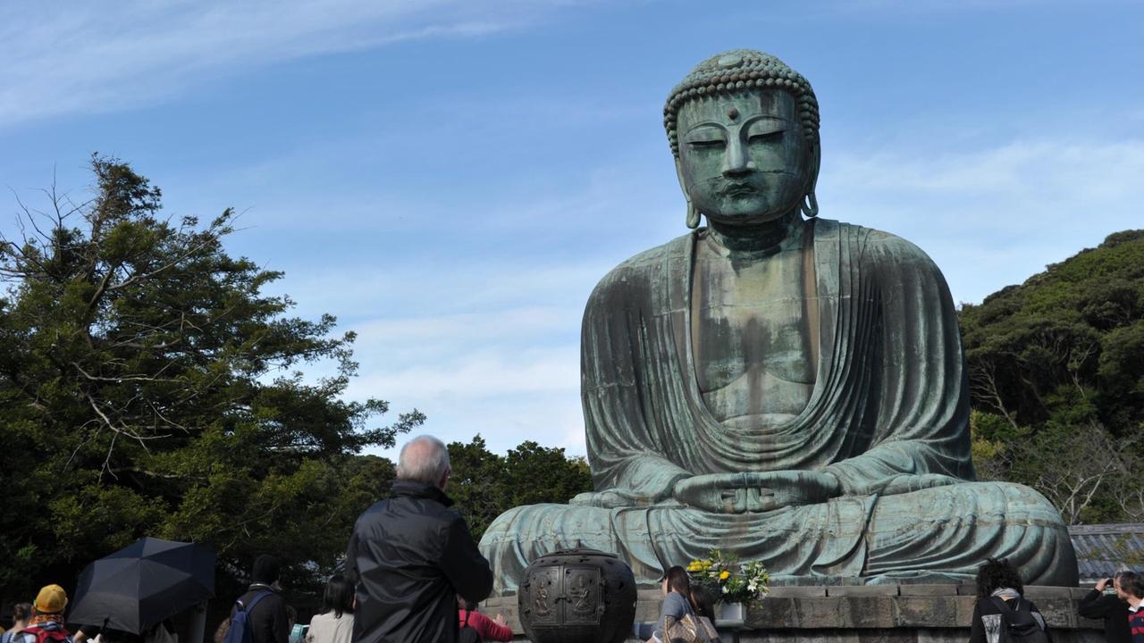 Touristen beobachten eine Buddha-Statue am Kotoku-in Tempel in Kamakura, Präfektur Kanagawa im Osten Japans. Die 11,5m hohe Bronze Statue wurde im Jahr 1252 konstruiert und ist die zweitgrößte Buddha Statue in Japan nach dem großen Buddha in Nara. Touristen beobachten eine Buddha-Statue am Kotoku-in Tempel in Kamakura, Präfektur Kanagawa im Osten Japans. Die 11,5m hohe Bronze Statue wurde im Jahr 1252 konstruiert und ist die zweitgrößte Buddha Statue in Japan nach dem großen Buddha in Nara.