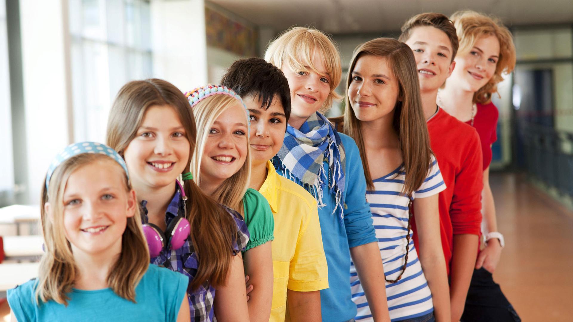 Das Bild zeigt eine Gruppe von Schülern in einem Schulgebäude. Das Bild zeigt eine Gruppe von Schülern in einem Schulgebäude.
