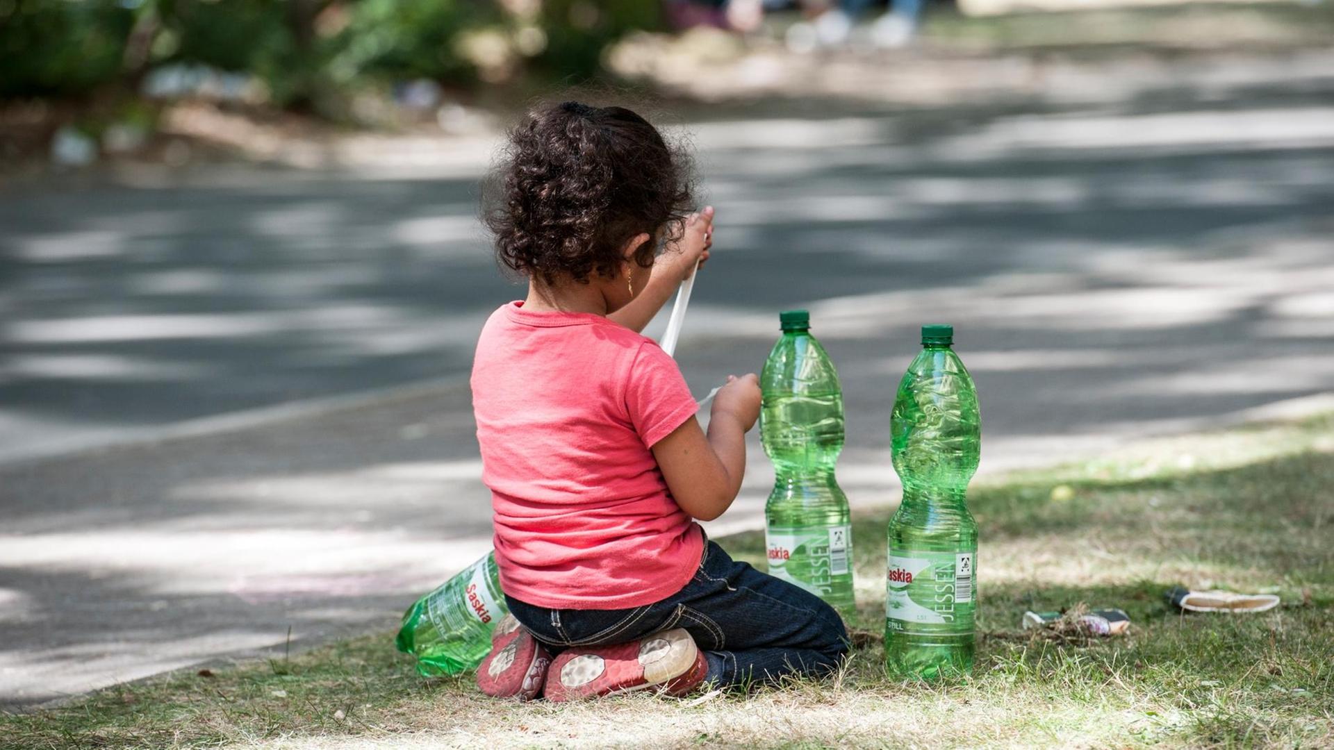 Ein Flüchtlingskind sitzt in Berlin auf dem Gelände des Landesamtes für Gesundheit und Soziales auf einem Grünstreifen. Ein Flüchtlingskind sitzt in Berlin auf dem Gelände des Landesamtes für Gesundheit und Soziales auf einem Grünstreifen.