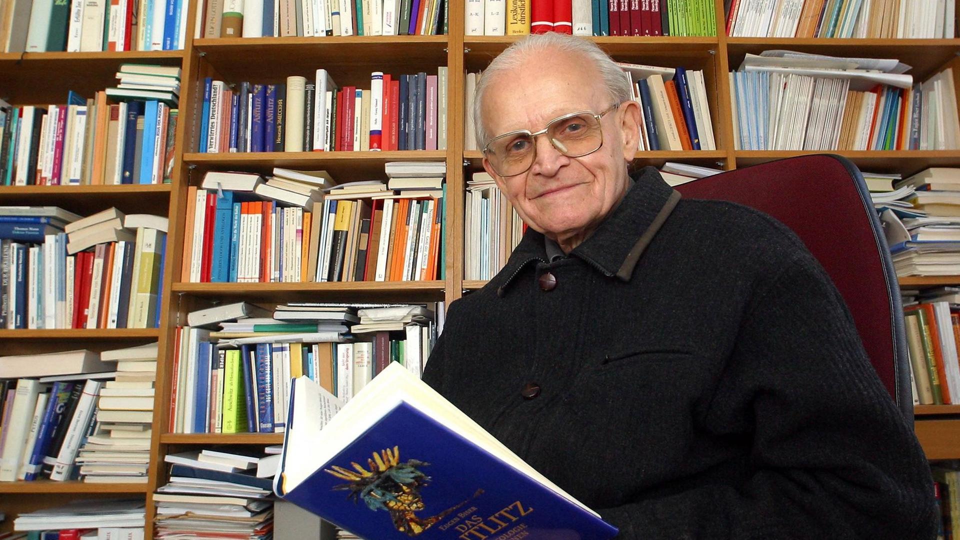 Theologe Prof. Eugen Biser mit einem Buch in seinem Büro