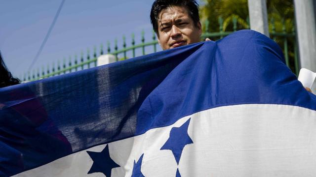 Ein Mann hält eine Flagge von Honduras in die Luft.