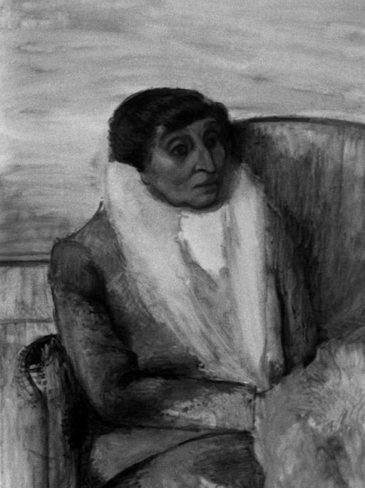 Dora Maar in ihrem Atelier, neben einem Gemälde, das eine ältere Frau in einem Sessel zeigt.