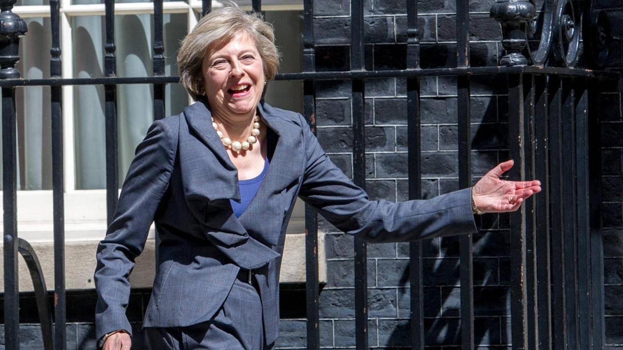 Theresa May geht lachend am Zaun eines Gebäudes vorbei Theresa May geht lachend am Zaun eines Gebäudes vorbei