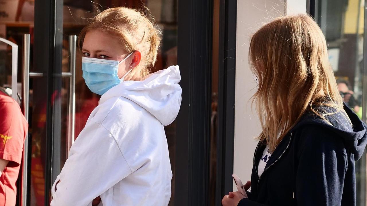 Zwei junge Frauen stehen in Berlin vor einem Bekleidungsgeschaeft Schlange mit Abstand zueinander und mit Masken gegen das neuartige Coronavirus. Zwei junge Frauen stehen in Berlin vor einem Bekleidungsgeschaeft Schlange mit Abstand zueinander und mit Masken gegen das neuartige Coronavirus.