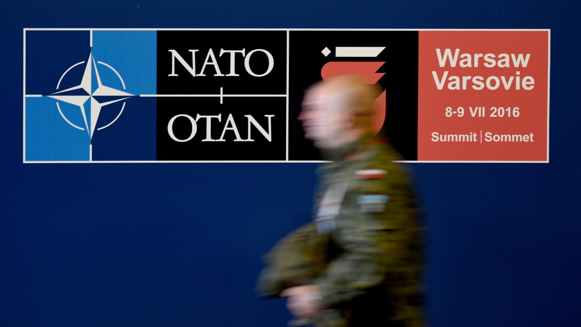 Ein polnischer Soldat geht am auf dem Gelände des Nationalstadions in Warschau an einem Schild des Nato-Gipfels entlang. Ein polnischer Soldat geht am auf dem Gelände des Nationalstadions in Warschau an einem Schild des Nato-Gipfels entlang.