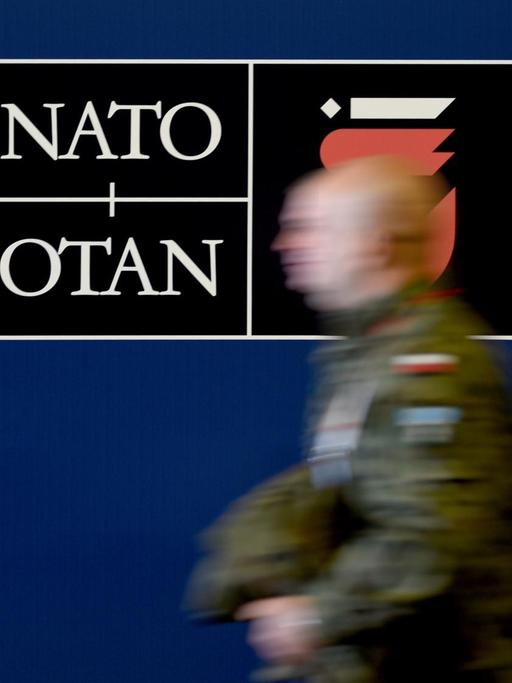 Ein polnischer Soldat geht am auf dem Gelände des Nationalstadions in Warschau an einem Schild des Nato-Gipfels entlang.