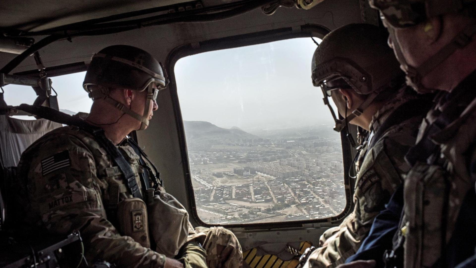 Amerikanische Soldaten schauen aus einem Helikopter auf Afghanistans Hauptstadt Kabul herunter Amerikanische Soldaten schauen aus einem Helikopter auf Afghanistans Hauptstadt Kabul herunter
