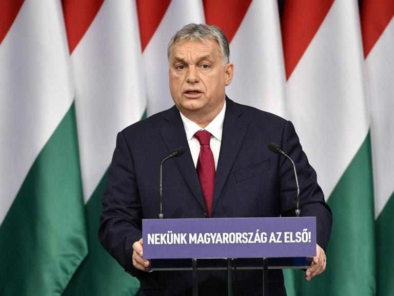 Viktor Orban, Ministerpräsident von Ungarn, steht an einem Rednerpult. Im Hintergrund mehrere ungarische Flaggen.
