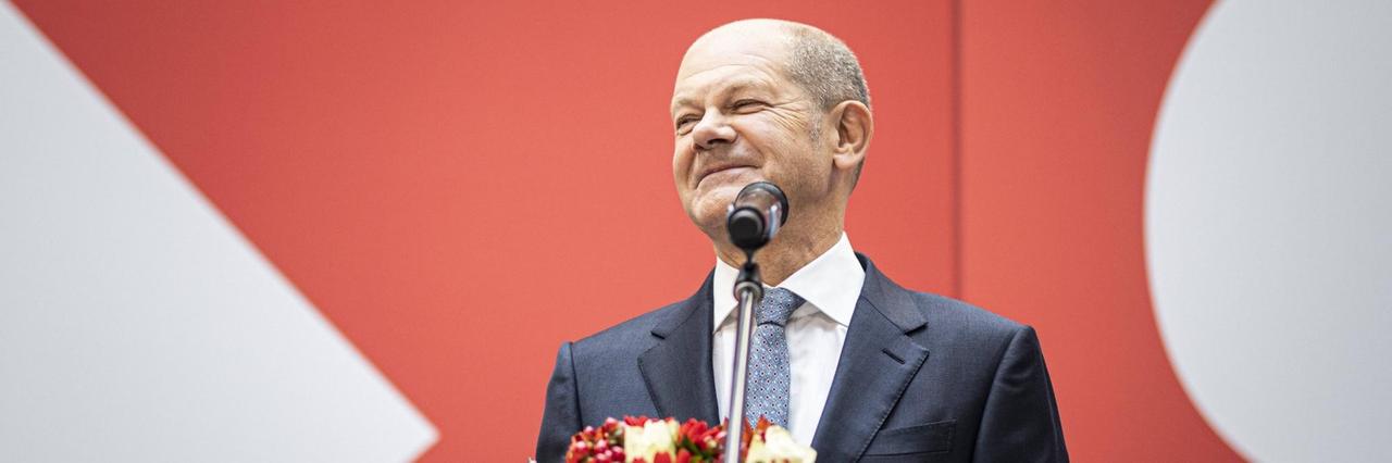 Der Kanzler-Kandidat von der SPD, Olaf Scholz hält einen Blumen-Strauß in der Hand und lächelt. Der Kanzler-Kandidat von der SPD, Olaf Scholz hält einen Blumen-Strauß in der Hand und lächelt.