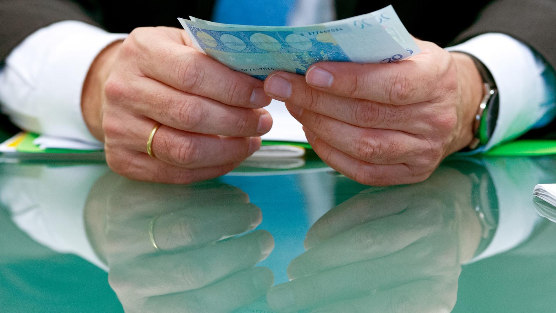 Sichergestellte, gefälschte Euro-Banknoten hält Bundesbank-Vorstand Carl-Ludwig Thiele bei der Bundesbank in Frankfurt am Main in den Händen und spiegelt sich dabei in der Tischplatte. Sichergestellte, gefälschte Euro-Banknoten hält Bundesbank-Vorstand Carl-Ludwig Thiele bei der Bundesbank in Frankfurt am Main in den Händen und spiegelt sich dabei in der Tischplatte.