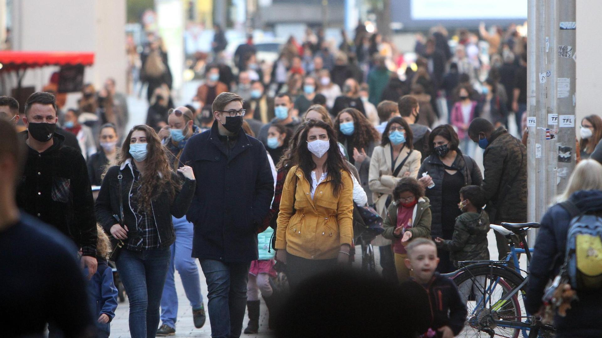 Menschen mit Masken laufen durch die Fußgängerzone Neuhauser Straße am Karlstor in der Innenstadt von München. Menschen mit Masken laufen durch die Fußgängerzone Neuhauser Straße am Karlstor in der Innenstadt von München.