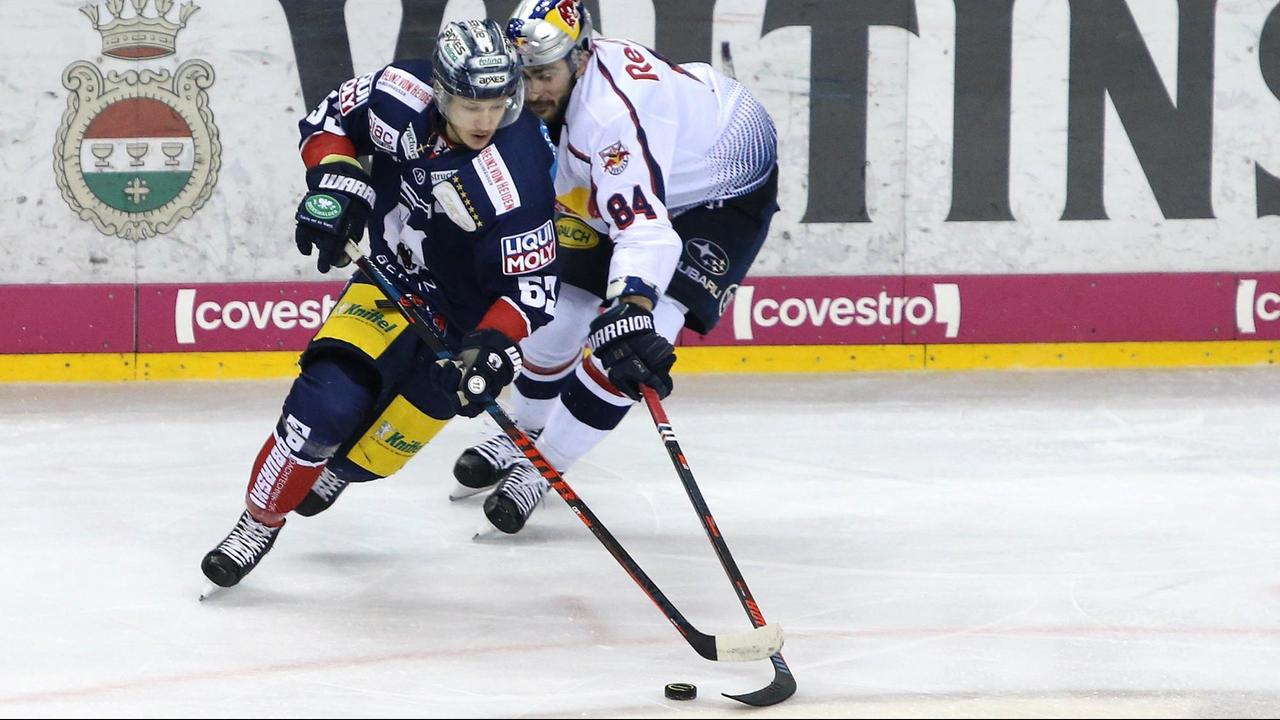 Der Berliner Eishockeyspieler Eric Mik (l) spielt mit Trevor Parkes vom EHC Red Bull München um den Puck. 