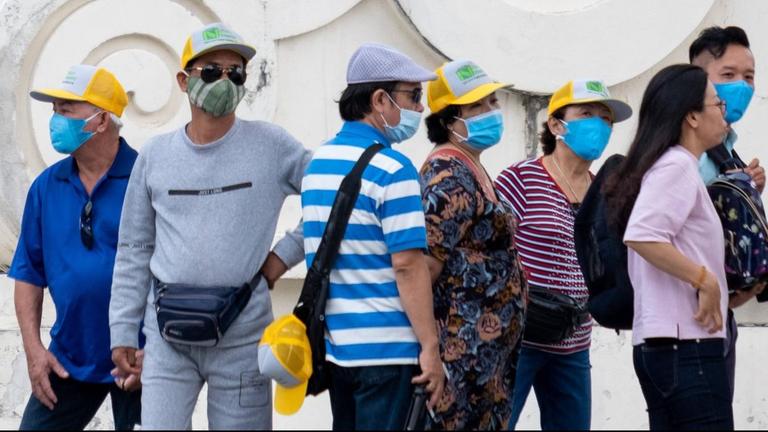 Eine Touristengruppe in Taiwan in Freizeitkleidung und mit chirurgischen Gesichtsschutzmasken.