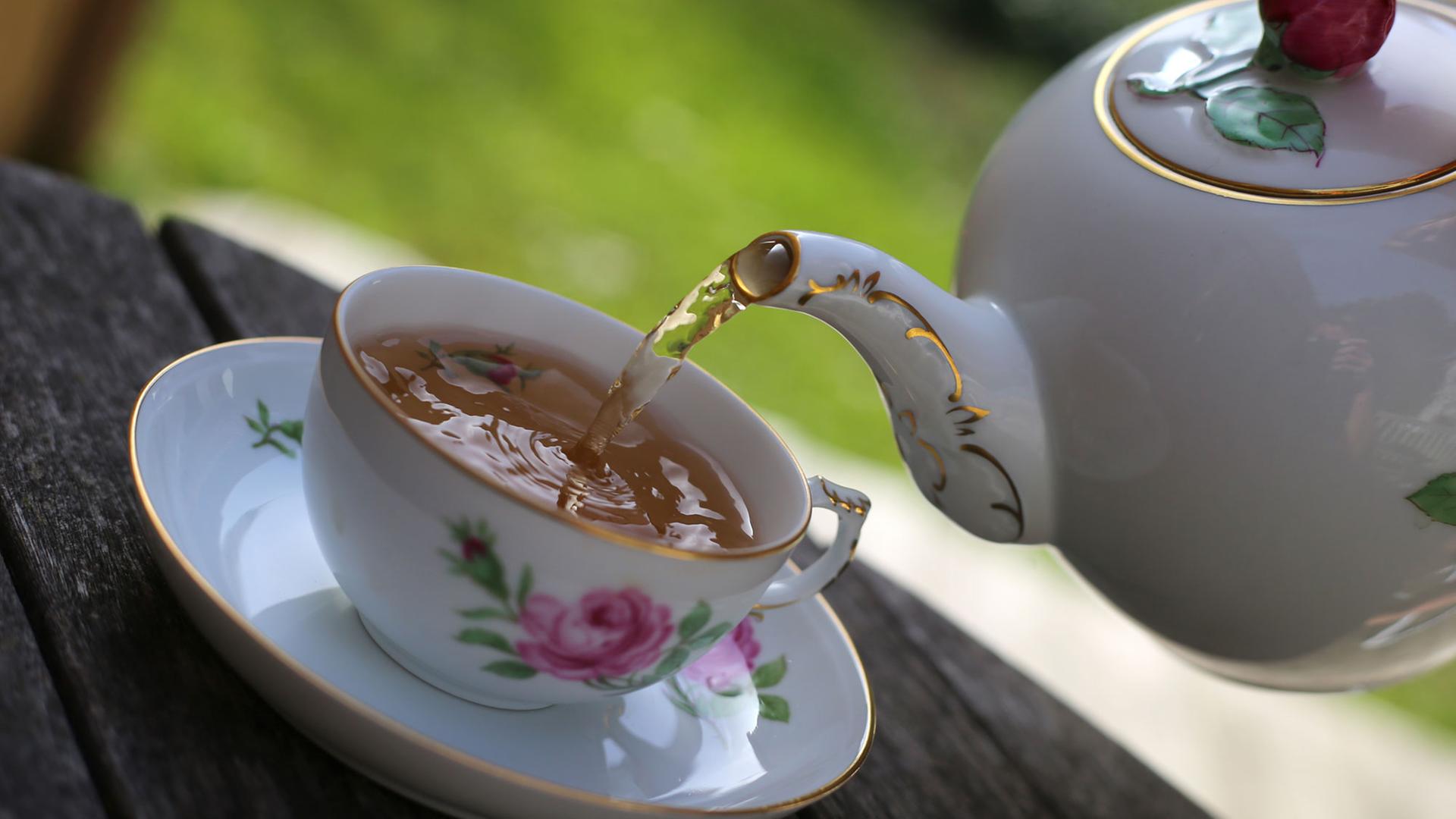 Schwarzer Tee wird in eine Teetasse gefüllt. Schwarzer Tee wird in eine Teetasse gefüllt.