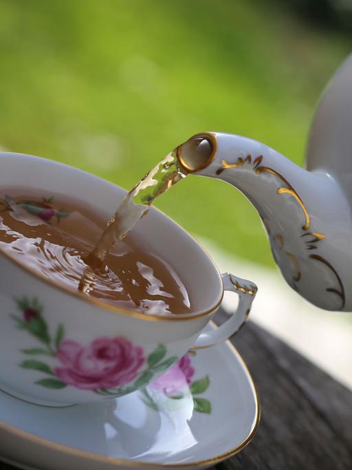 Schwarzer Tee wird in eine Teetasse gefüllt.