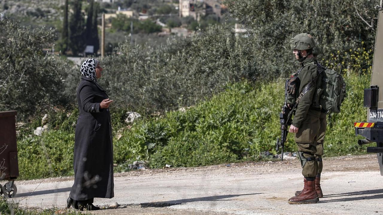 In der Nähe der jüdischen Siedlung Ariel im Westjordanland spricht eine Palästinenserin mit einem israelischen Soldaten In der Nähe der jüdischen Siedlung Ariel im Westjordanland spricht eine Palästinenserin mit einem israelischen Soldaten