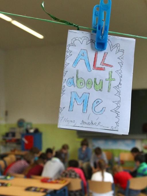 Von Schülerinnen und Schülern auf englisch gestaltete persönliche Heftchen hängen während des Unterrichtes in einem Klassenzimmer an einer Leine