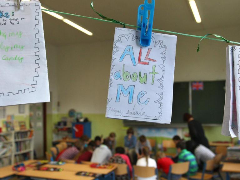 Von Schülerinnen und Schülern auf englisch gestaltete persönliche Heftchen hängen während des Unterrichtes in einem Klassenzimmer an einer Leine