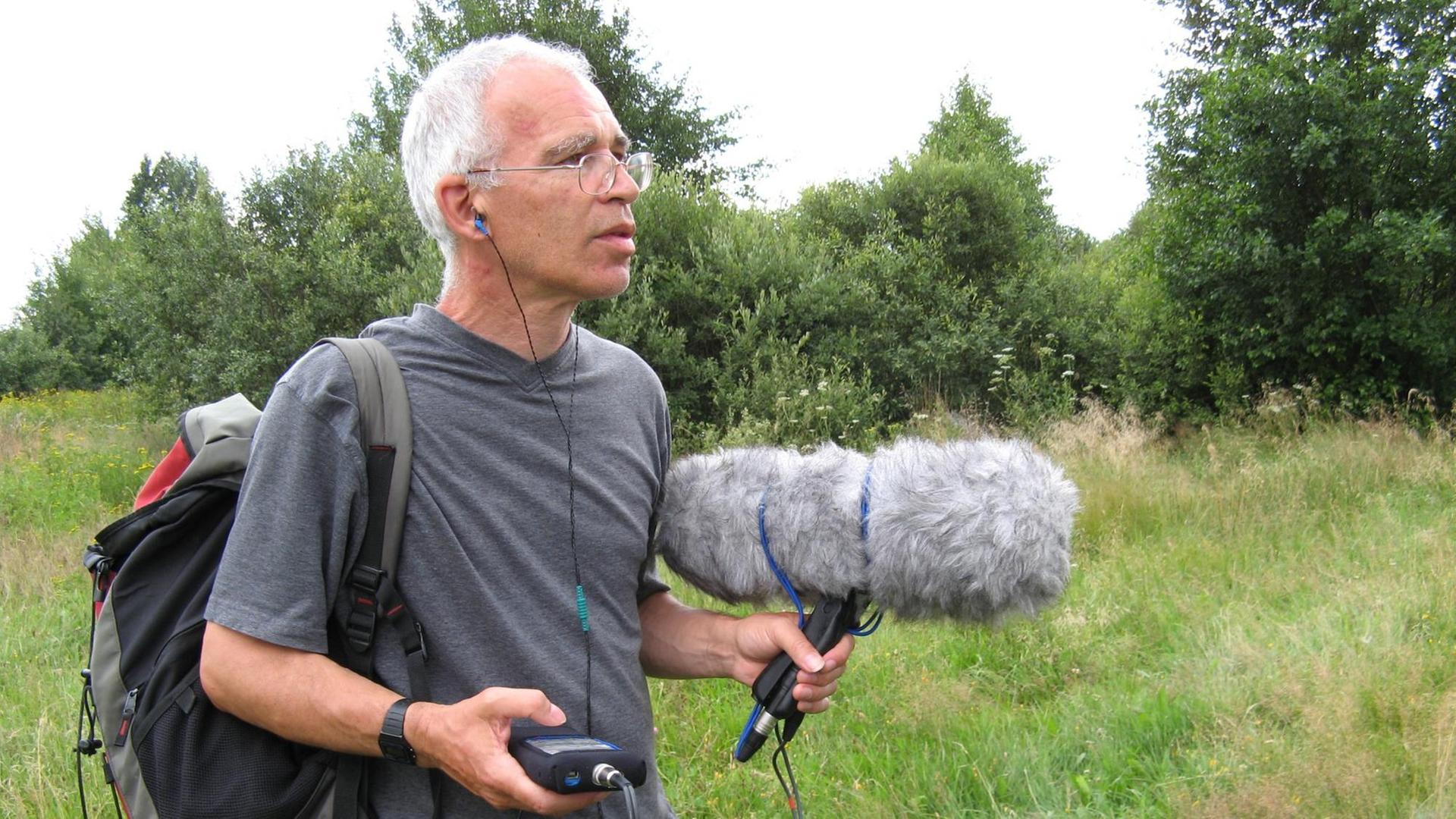 Peter Cusack mit Aufnahmegerät und großem Windschutz bei Feldaufnahmen in offener Landschaft