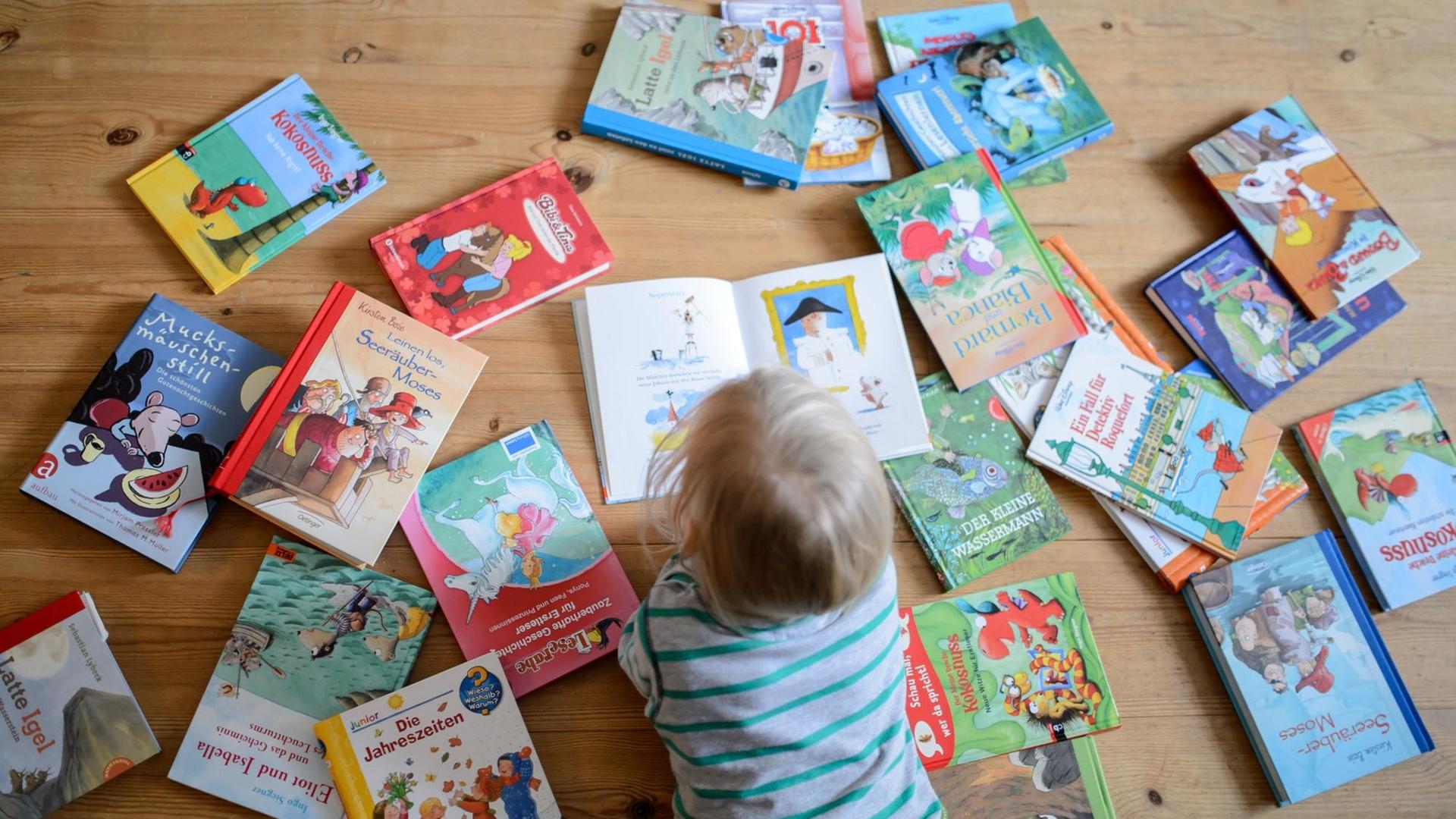 ILLUSTRATION: Ein Kind liegt zwischen vielen Büchern und schaut sich ein Buch an, aufgenommen am 28.01.2015 in Dresden (Sachsen). Foto: Thomas Eisenhuth - model released -