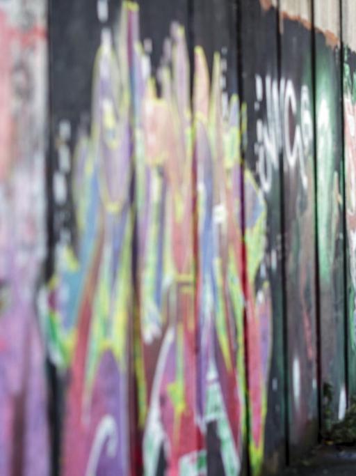 Ein Graffiti-Künstler besprüht am 27.02.2017 in einem pro-britische Teil von Belfast (Nordirland) eine Friedensmauer. Gewaltige Mauern und Metallzäune schlängeln sich durch Belfast, manche über zwölf Meter hoch und gekrönt von Stacheldraht. Sie trennen Wohngebiete voneinander, schnurgerade oder im Zickzack-Kurs. Die Katholiken leben auf der einen Seite, die Protestanten auf der anderen.