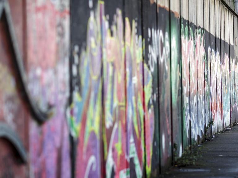 Ein Graffiti-Künstler besprüht am 27.02.2017 in einem pro-britische Teil von Belfast (Nordirland) eine Friedensmauer. Gewaltige Mauern und Metallzäune schlängeln sich durch Belfast, manche über zwölf Meter hoch und gekrönt von Stacheldraht. Sie trennen Wohngebiete voneinander, schnurgerade oder im Zickzack-Kurs. Die Katholiken leben auf der einen Seite, die Protestanten auf der anderen.