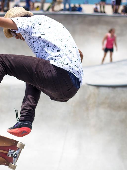 Ein Skater fliegt auf einer Skate-Anlage in die Luft.
