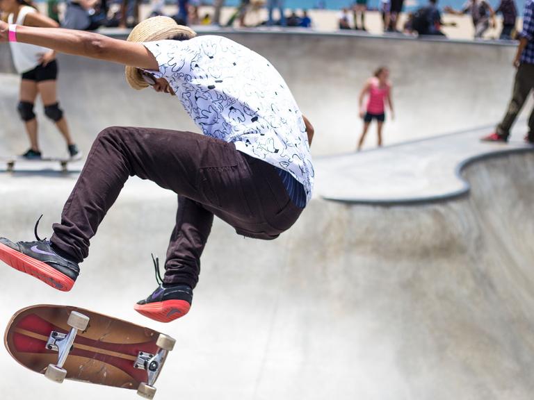 Ein Skater fliegt auf einer Skate-Anlage in die Luft.