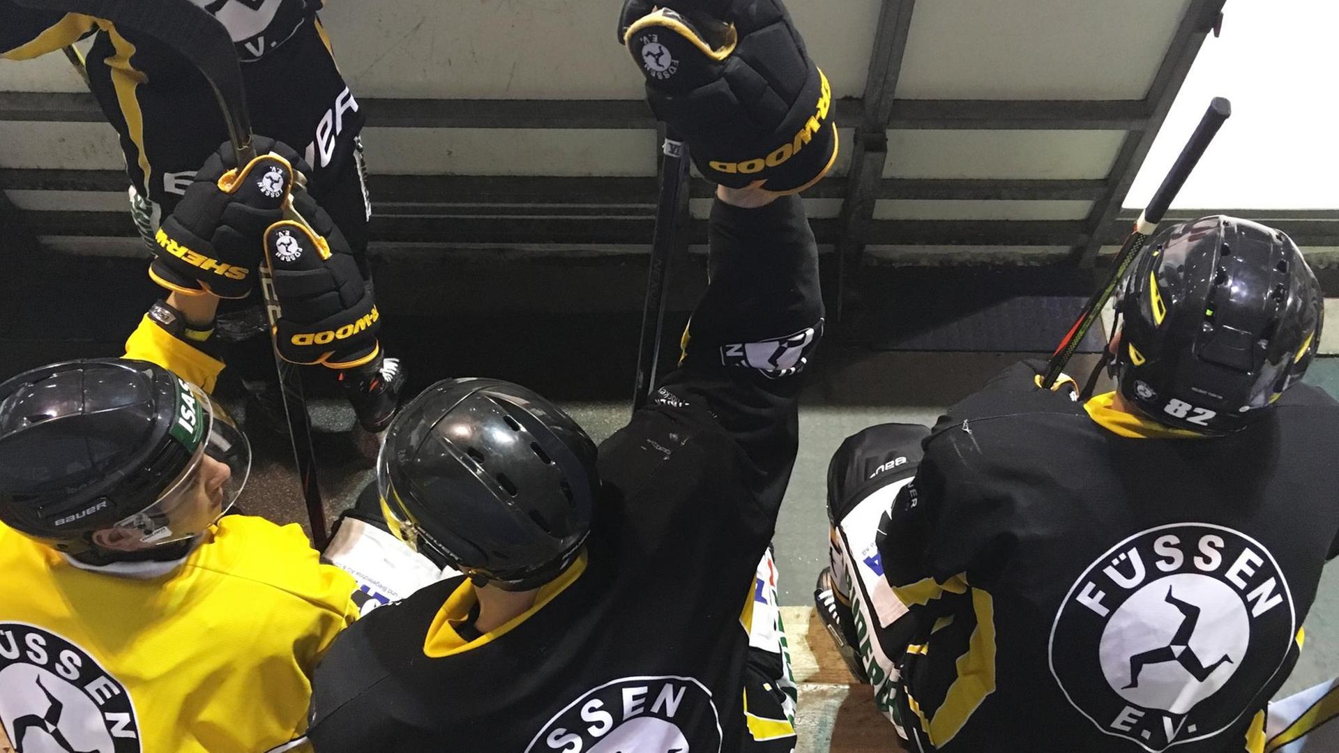 Drei Eishockeyspieler des EV Füssen sitzen, in schwarz gelben Trikots, auf der Spielerbank. Drei Eishockeyspieler des EV Füssen sitzen, in schwarz gelben Trikots, auf der Spielerbank.