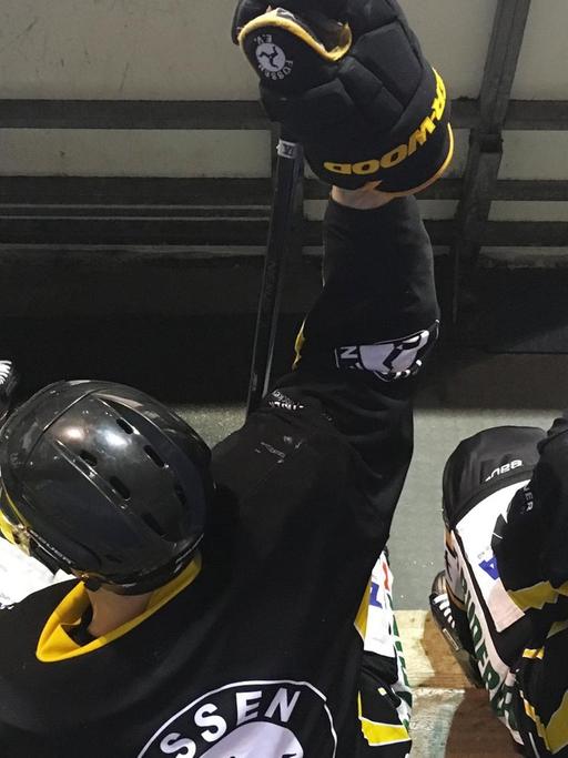 Drei Eishockeyspieler des EV Füssen sitzen, in schwarz gelben Trikots, auf der Spielerbank.