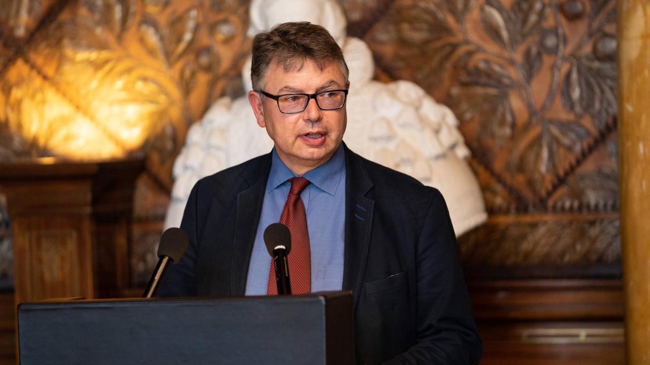 Prof. Dr. Jürgen Zimmerer, Leiter der Forschungsstelle Hamburgs (post-)koloniales Erbe der Universität Hamburg steht an einem Rednerpult. Prof. Dr. Jürgen Zimmerer, Leiter der Forschungsstelle Hamburgs (post-)koloniales Erbe der Universität Hamburg steht an einem Rednerpult.