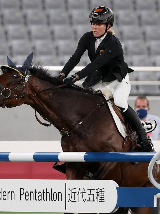 Das Bild zeigt die Reiterin Annika Schleu. Sie sitzt auf einem Pferd. Das Pferd will nicht über ein Hindernis springen. Das war bei den Olmpischen Spielen.   