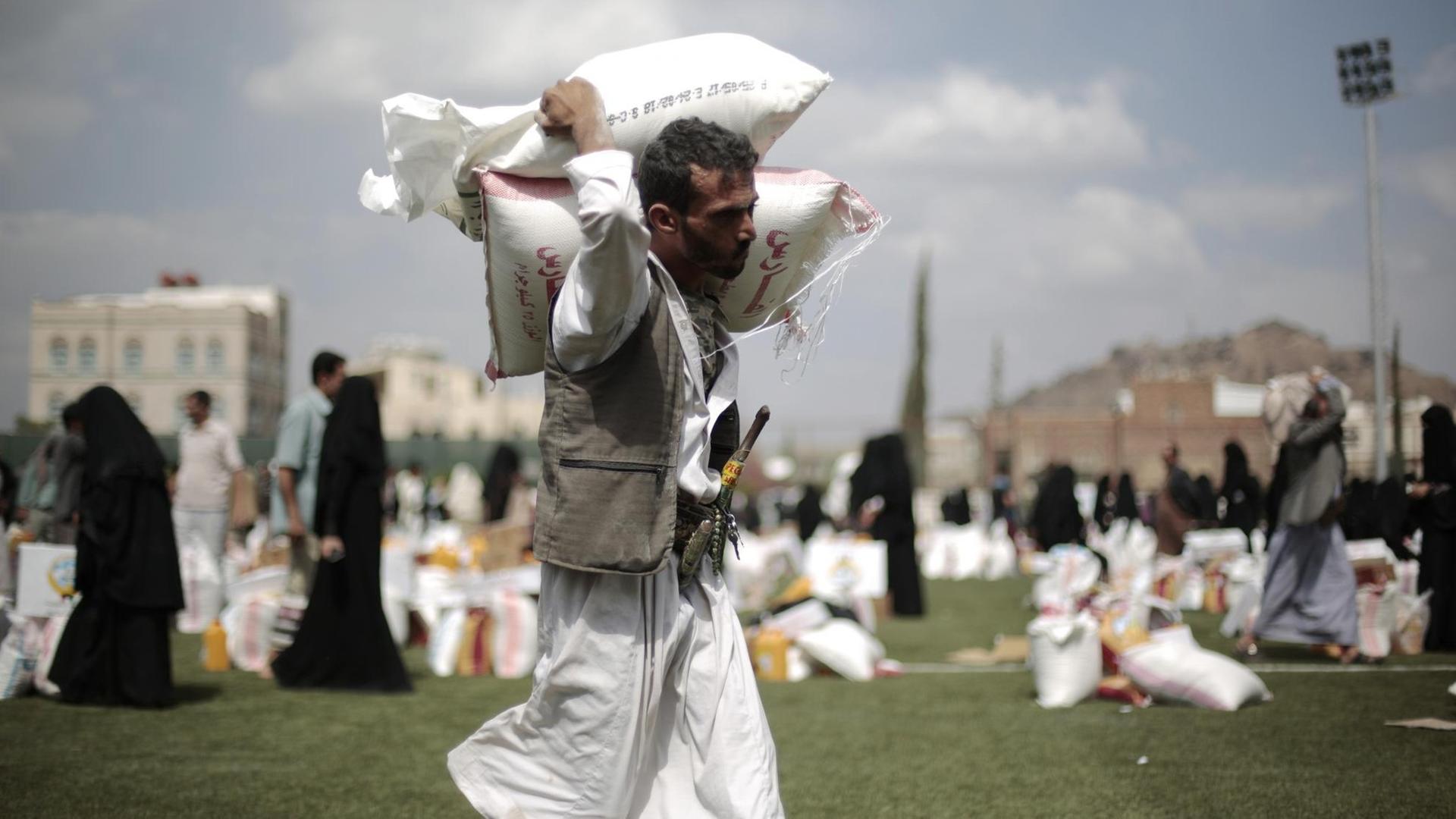 Ein Mann trägt in Sanaa (Jemen) Säcke mit Getreide.