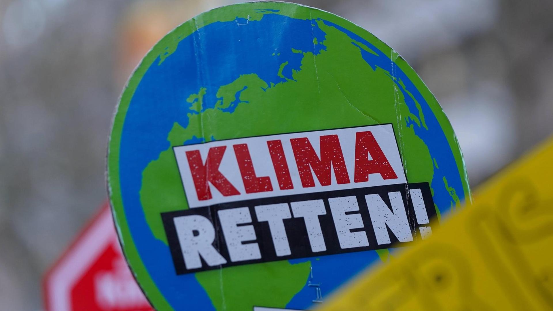 Ein Plakat auf einer Klima-Demo zeigt eine Weltkugel, auf der "Klima retten" steht" Ein Plakat auf einer Klima-Demo zeigt eine Weltkugel, auf der "Klima retten" steht"