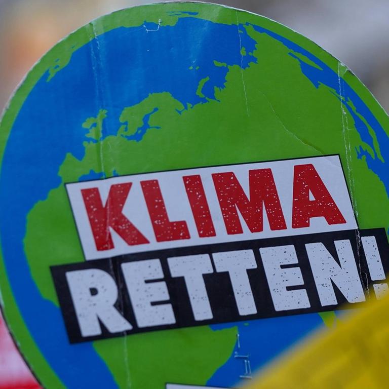 Ein Plakat auf einer Klima-Demo zeigt eine Weltkugel, auf der "Klima retten" steht"