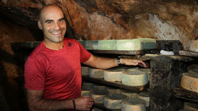 Javier Diaz Bada steht vor einem Regal mit vom Blauschimmel überzogenem Cabrales Käse in der familieneigenen Höhle Javier Diaz Bada steht vor einem Regal mit vom Blauschimmel überzogenem Cabrales Käse in der familieneigenen Höhle