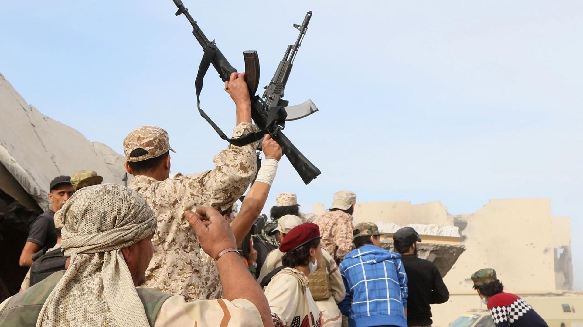 Mitglieder der regierungstreuen Truppen in Libyen schwingen triumphierend ihre Waffen.