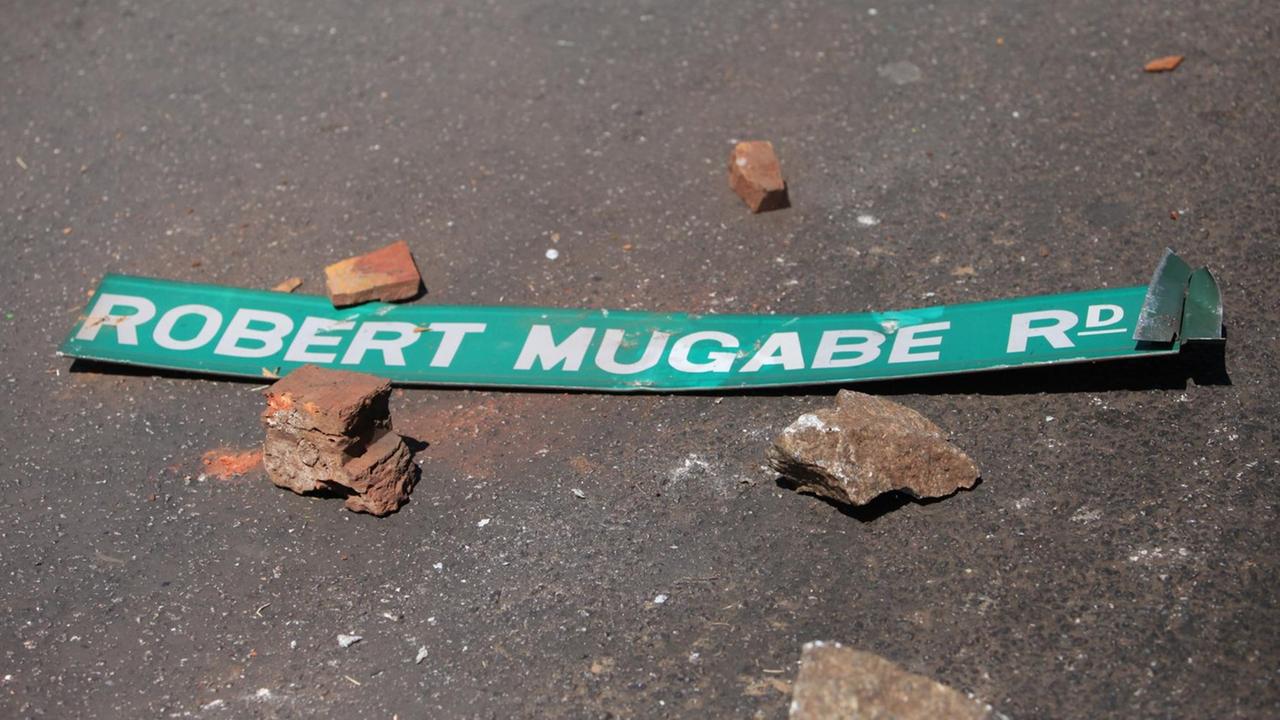 Ein Straßenschild mit dem Namen von Simbabwes Präsident Robert Mugabe liegt auf dem Boden in der Hauptstadt Harare. Dort war es nach einer Großkundgebung der Opposition zu schweren Unruhen gekommen. Ein Straßenschild mit dem Namen von Simbabwes Präsident Robert Mugabe liegt auf dem Boden in der Hauptstadt Harare. Dort war es nach einer Großkundgebung der Opposition zu schweren Unruhen gekommen.