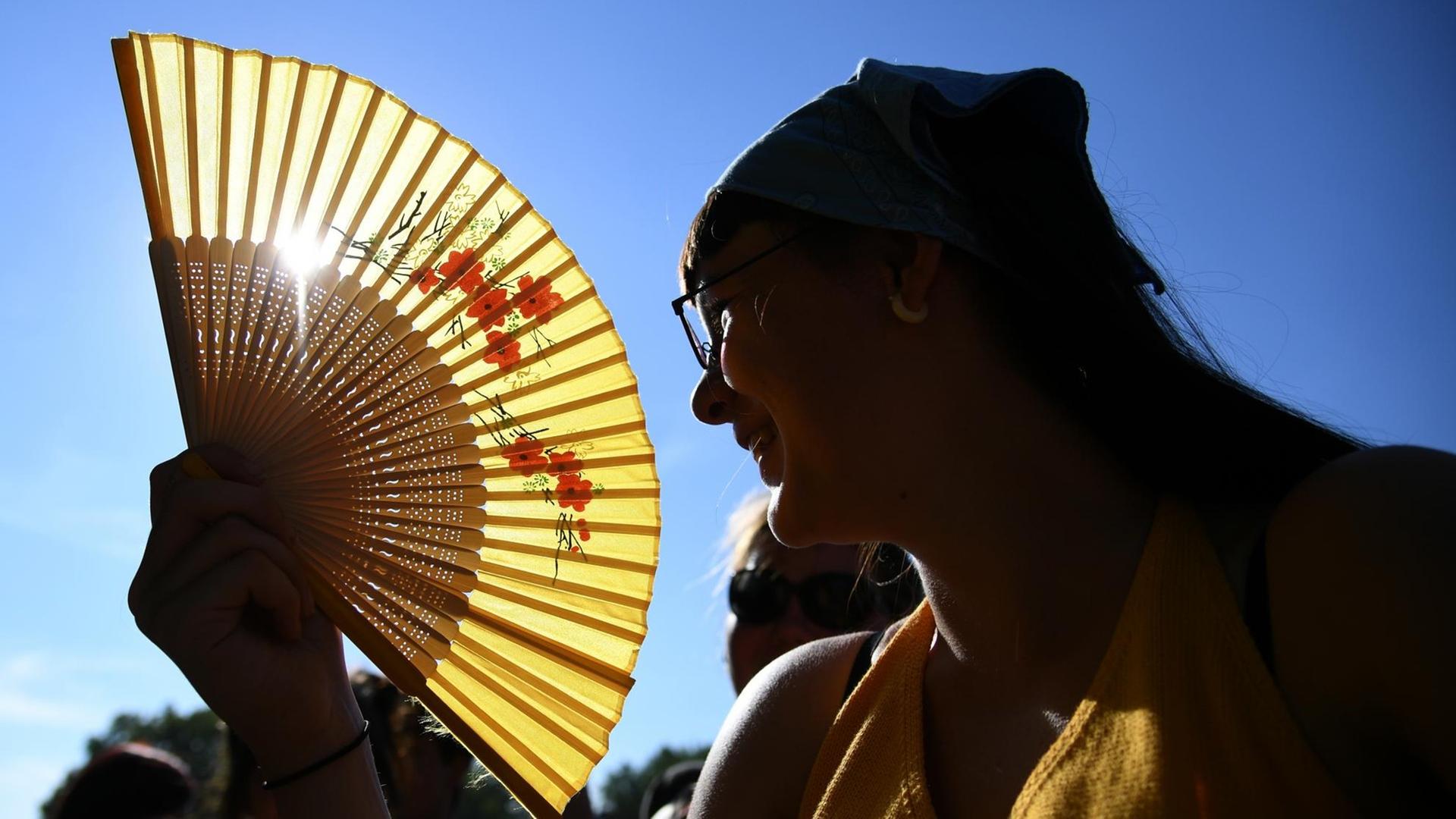 Das Bild zeigt eine Frau, die sich im Sommer kühle Luft zufächelt. Das Bild zeigt eine Frau, die sich im Sommer kühle Luft zufächelt.