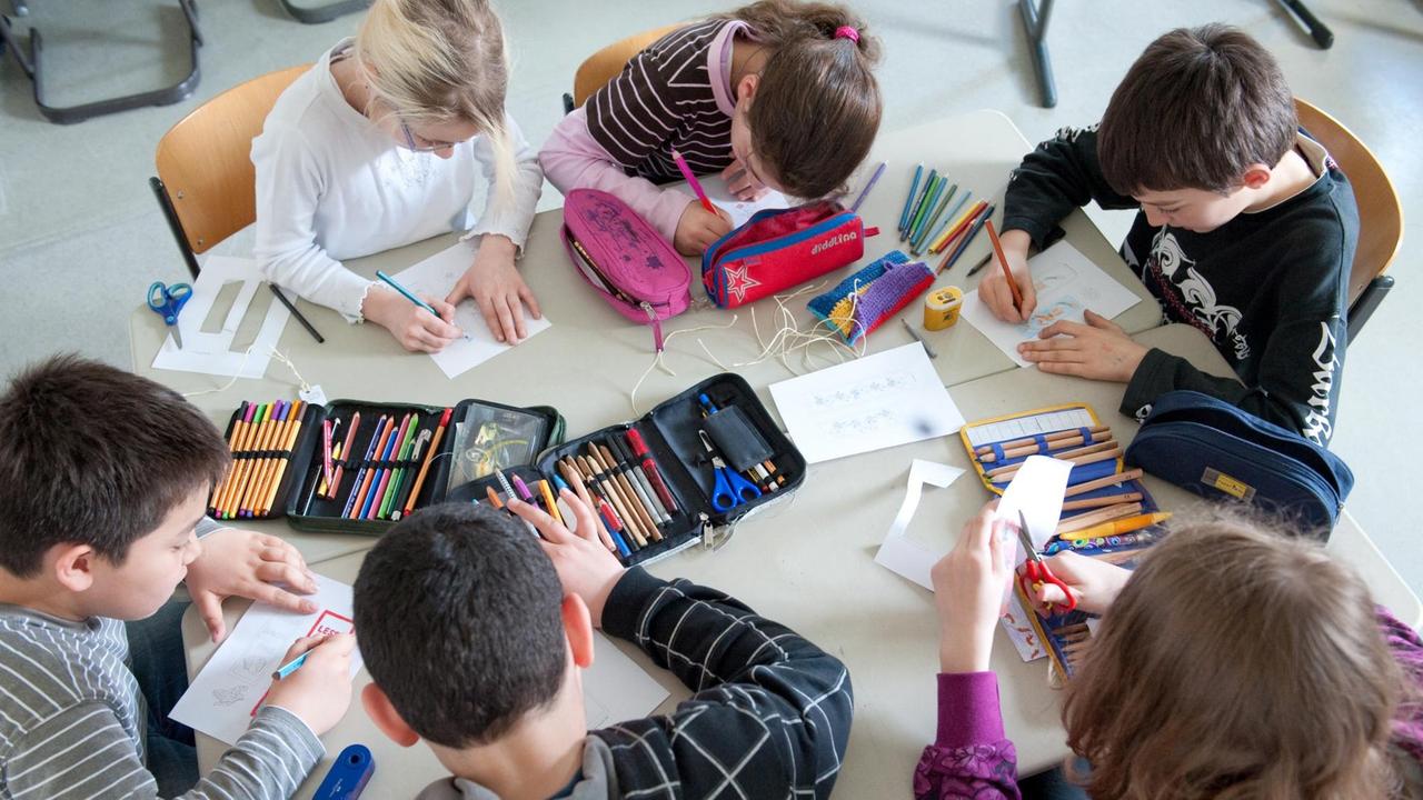 Schüler einer 5. Klasse der BiL-Privatschule in Stuttgart sitzen an einem Tisch und malen Schüler einer 5. Klasse der BiL-Privatschule in Stuttgart sitzen an einem Tisch und malen