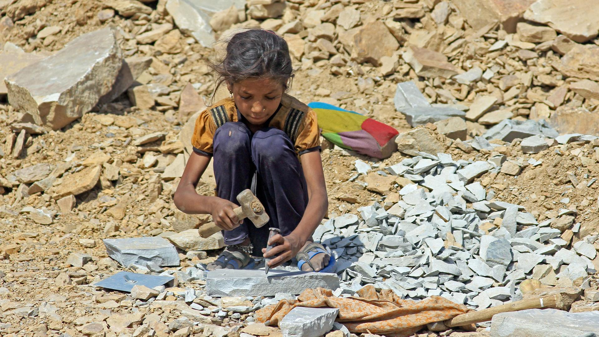 Ein etwa 8-jähriges Mädchen sitzt am 16.05.2013 in Kota, in der indischen Provinz Rajasthan, in einem Steinbruch und arbeitet mit Hammer und Meißel. Ein etwa 8-jähriges Mädchen sitzt am 16.05.2013 in Kota, in der indischen Provinz Rajasthan, in einem Steinbruch und arbeitet mit Hammer und Meißel.